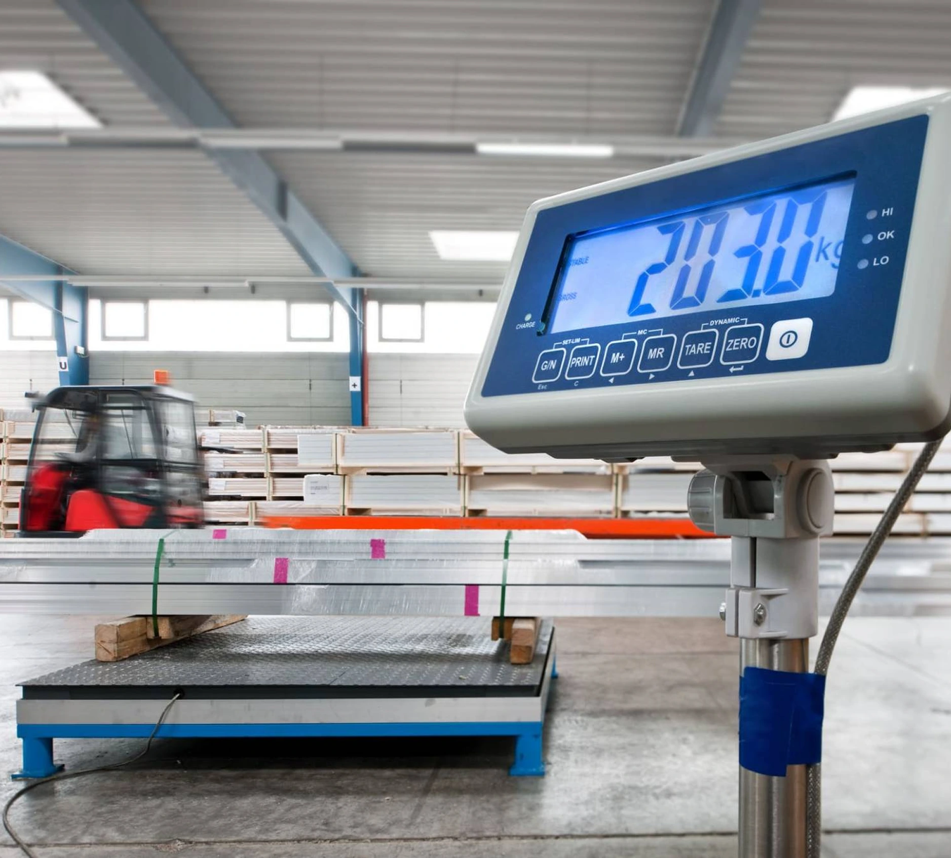 Indicateur de pesage électronique affichant 203 kg dans un entrepôt de stockage.